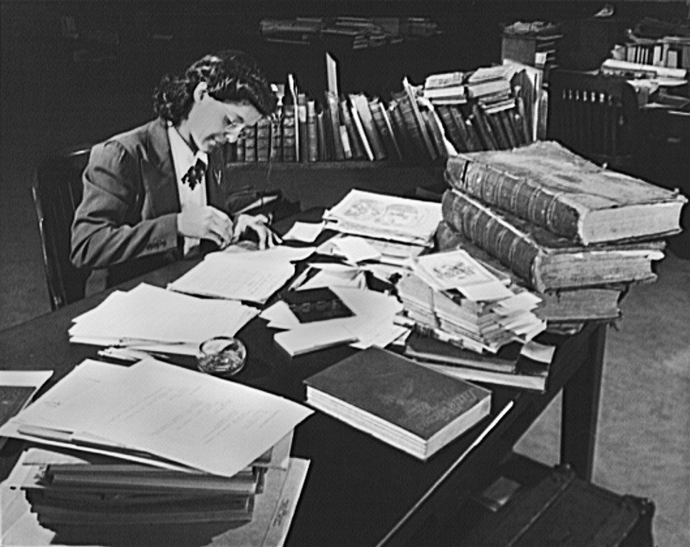 photo of Jewel Mazique seated at a table with a pile of books